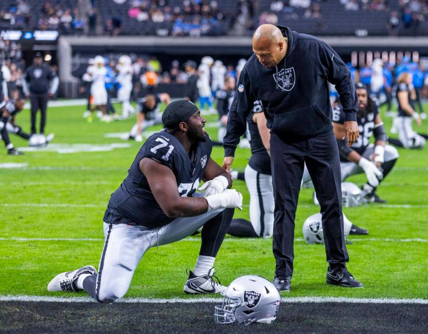 Raiders head coach Antonio Pierce chats with Raiders offensive tackle DJ Glaze (71) during warm ...