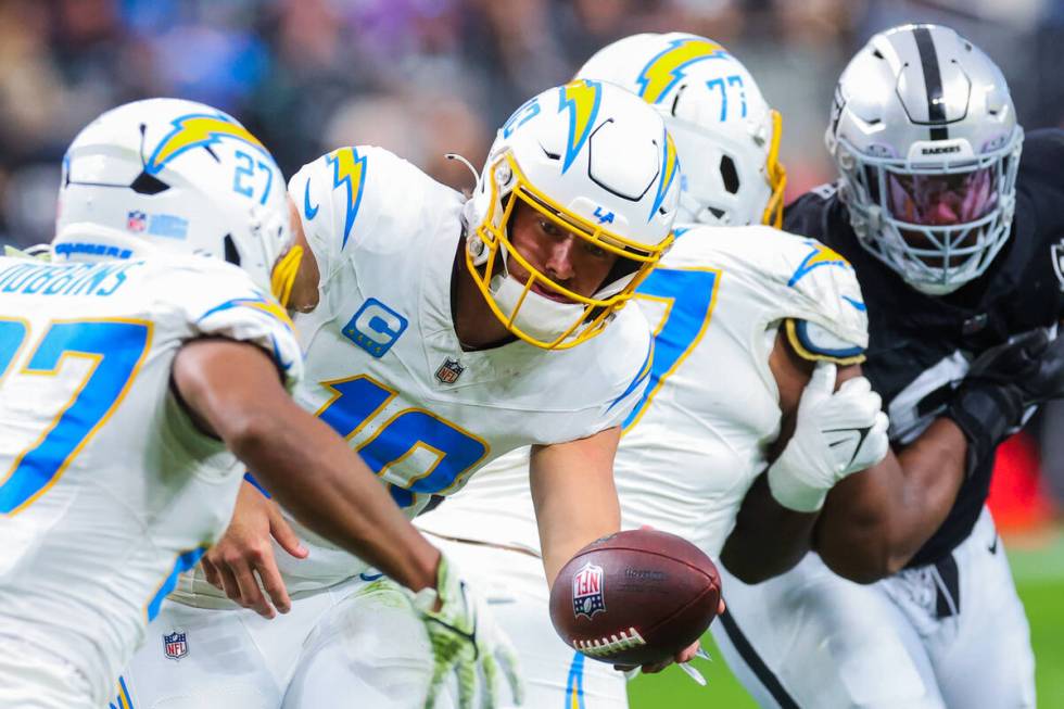 Los Angeles Chargers quarterback Justin Herbert (10) passes the ball off to Los Angeles Charger ...