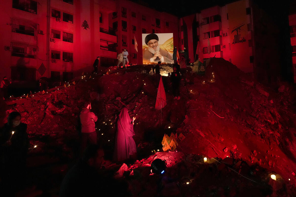 FILE - A woman lights candles at the site where former Hezbollah leader Hassan Nasrallah was ki ...