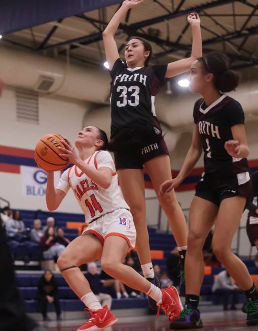 Bishop Gorman's Kenzee Holton (14) looks to shoot as Faith Lutheran's Emma Herpin (33) defends ...