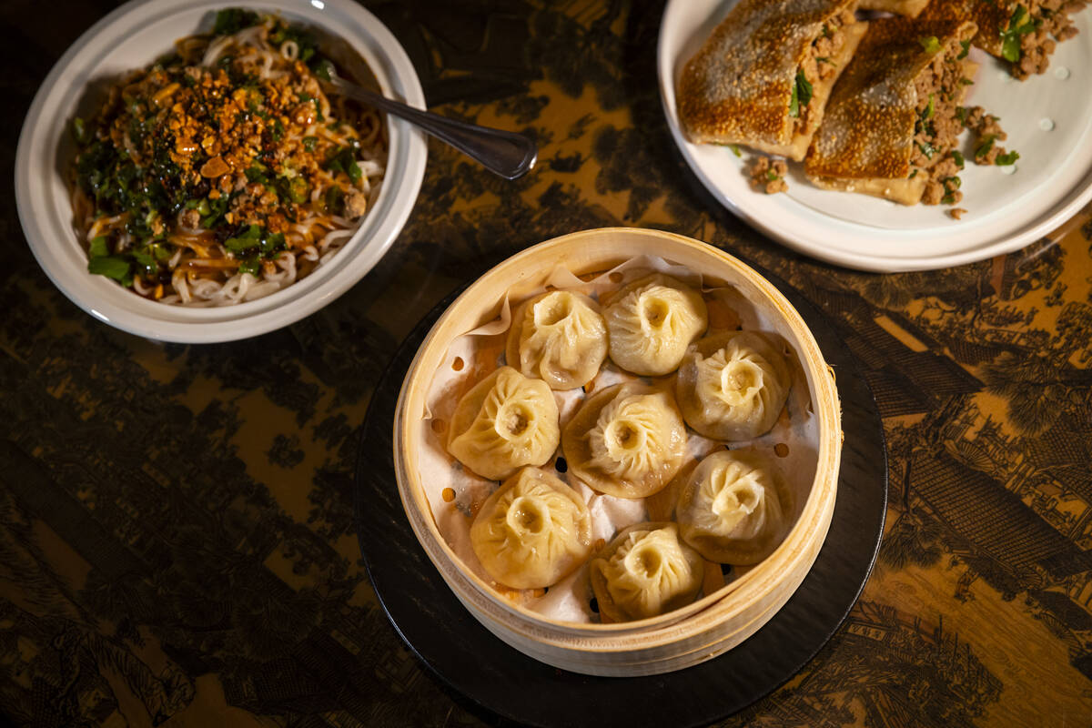 Pork soup dumplings, center, are pictured alongside dan dan noodles, left, and big mouth rolls ...