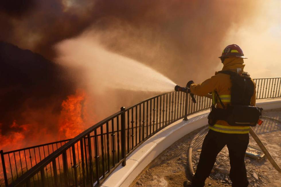 A firefighter makes a stand in front of the advancing Palisades Fire in the Pacific Palisades n ...