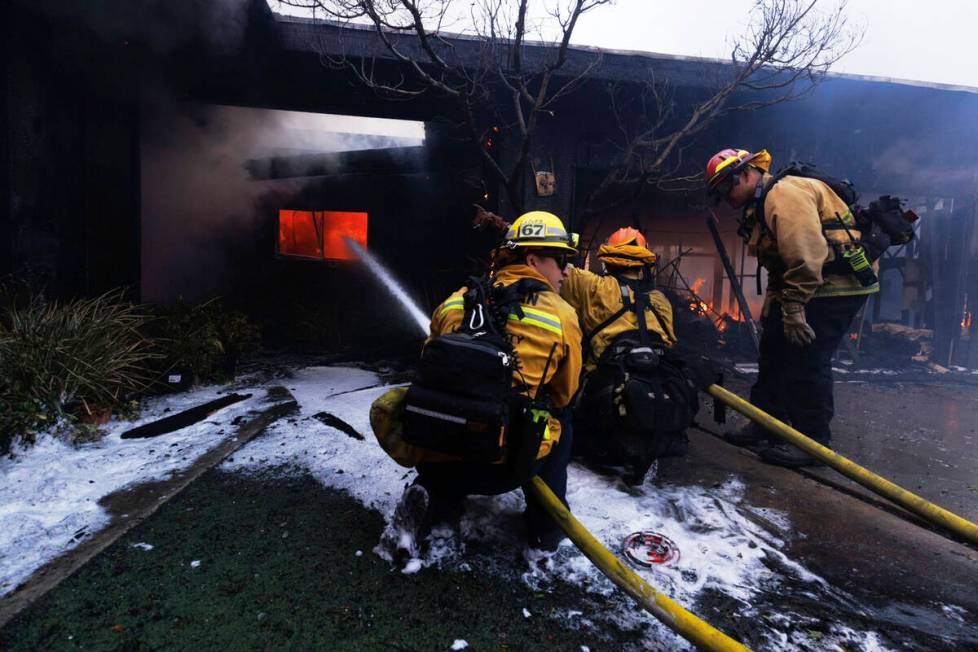 Firefighters battle the advancing Palisades Fire as it damages a residence in the Pacific Palis ...