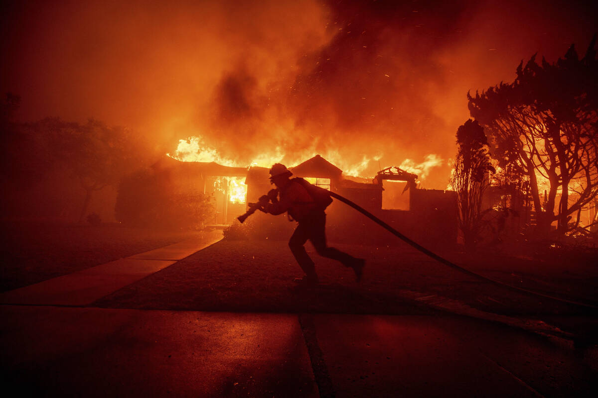 A firefighter battles the Palisades Fire as it burns a structure in the Pacific Palisades neigh ...