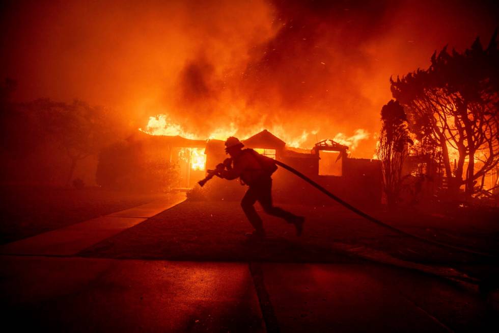 A firefighter battles the Palisades Fire as it burns a structure in the Pacific Palisades neigh ...