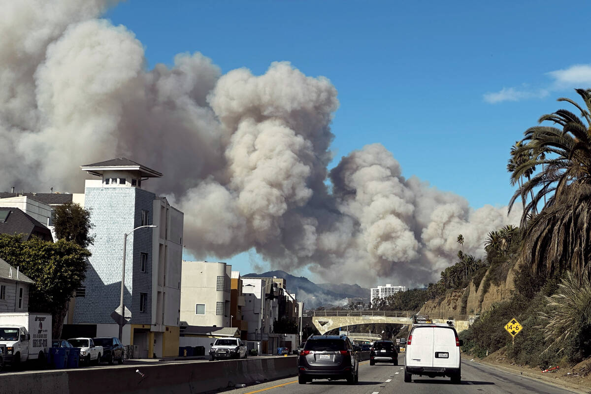 Heavy smoke from a brush fire in the Pacific Palisades rises over the Pacific Coast Highway in ...