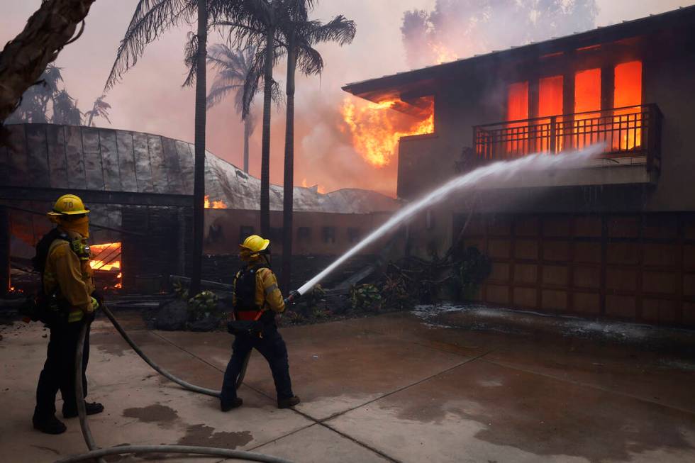 Firefighters hose down flames as the Palisades Fire destroys a residence in the Pacific Palisad ...