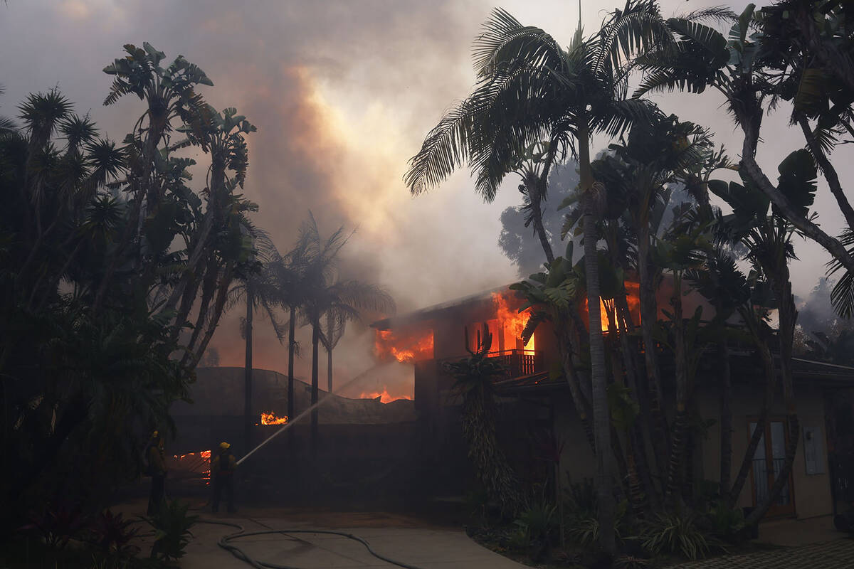 Firefighters hose down flames as the Palisades Fire destroys a residence in the Pacific Palisad ...