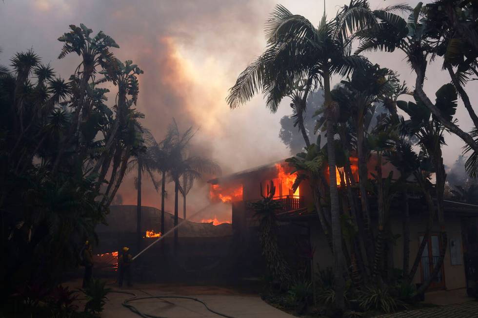 Firefighters hose down flames as the Palisades Fire destroys a residence in the Pacific Palisad ...