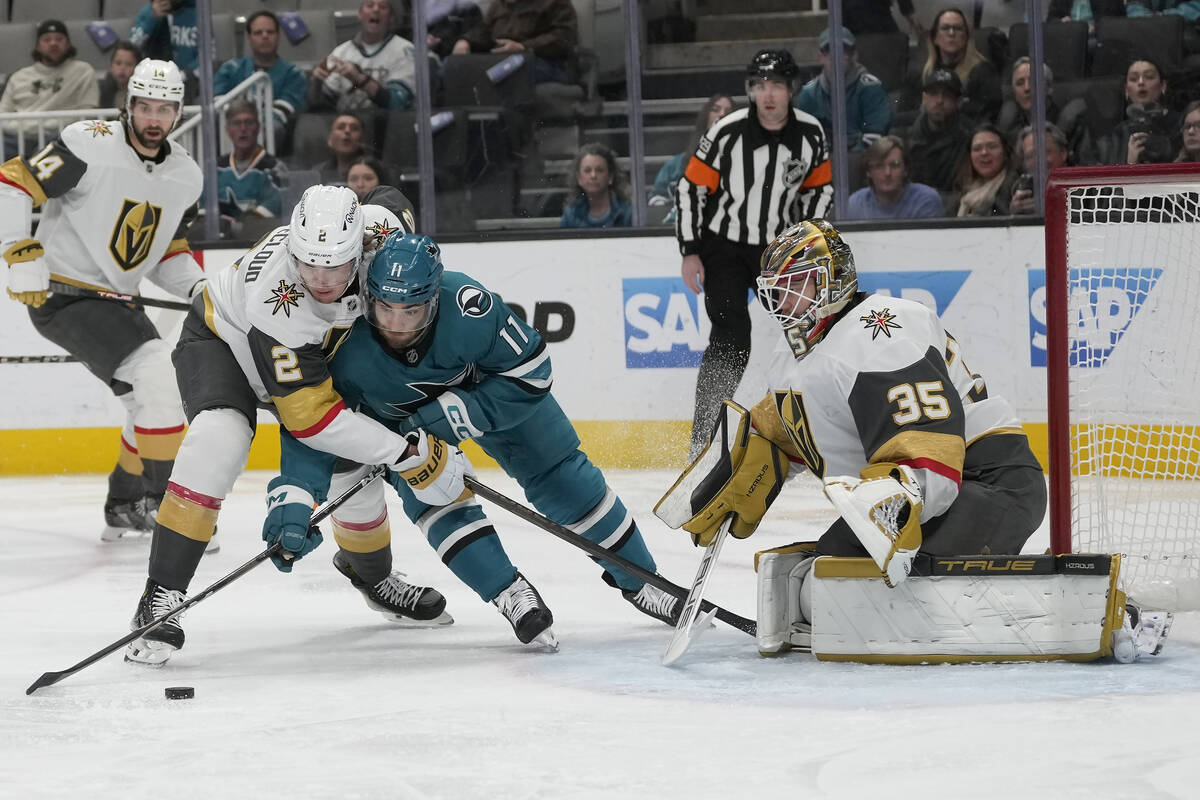 San Jose Sharks center Luke Kunin, middle, reaches for the puck between Vegas Golden Knights de ...