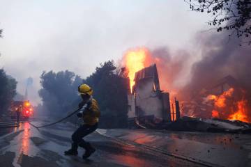 A firefighter battles the advancing Palisades Fire as it burns a structure in the Pacific Palis ...