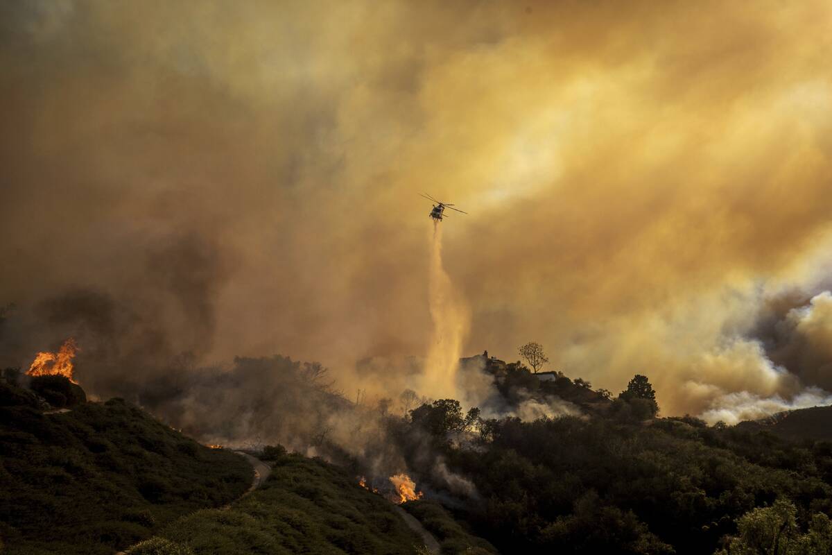 Water is dropped on the advancing Palisades Fire by helicopter in the Pacific Palisades neighbo ...