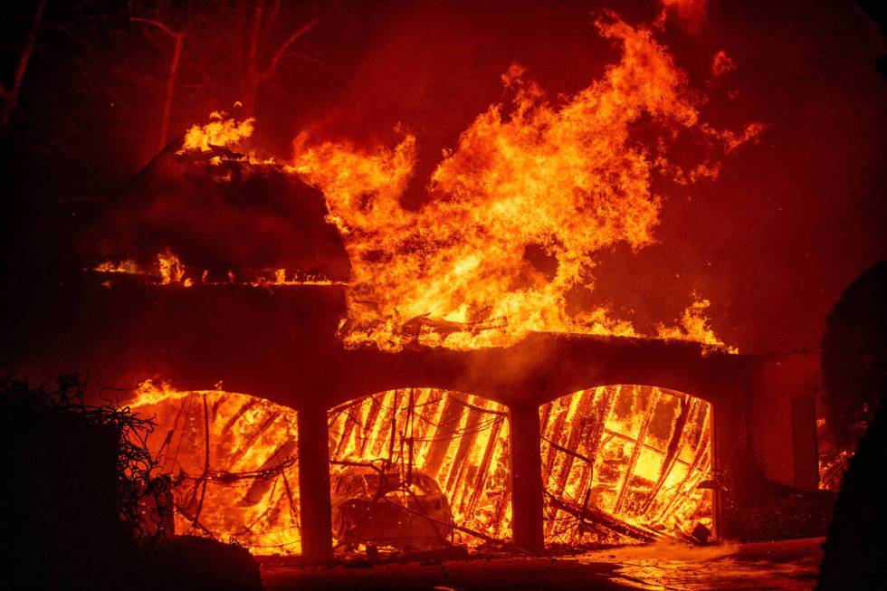 The Eaton Fire burns a residence Wednesday, Jan. 8, 2025 in Altadena, Calif. (AP Photo/Ethan Swope)