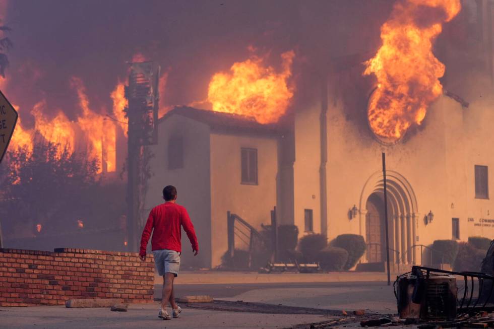 A man walks in front of the burning Altadena Community Church, Wednesday, Jan. 8, 2025, in the ...