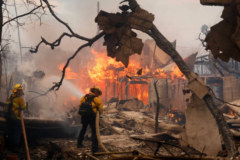 Firefighters battle the Palisades Fire as it burns a structure in the Pacific Palisades neighbo ...