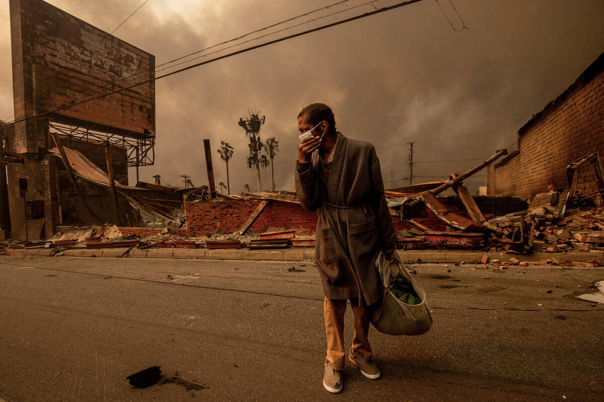 A man walks past a fire-ravaged business after the Eaton Fire swept through Wednesday, Jan. 8, ...