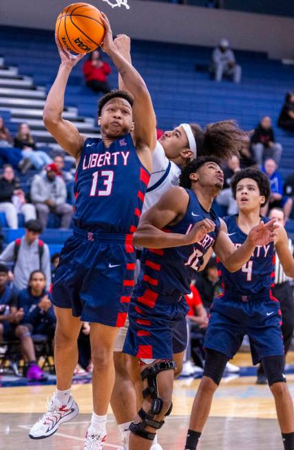 Liberty's Jaden Riley (13) posts up for a shot over Centennial's Jayonni Durrough (25) during t ...