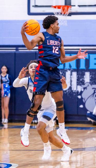 Liberty's Evan Hilliard (12) gets up high to pass over Centennial's Jayonni Durrough (25) duri ...