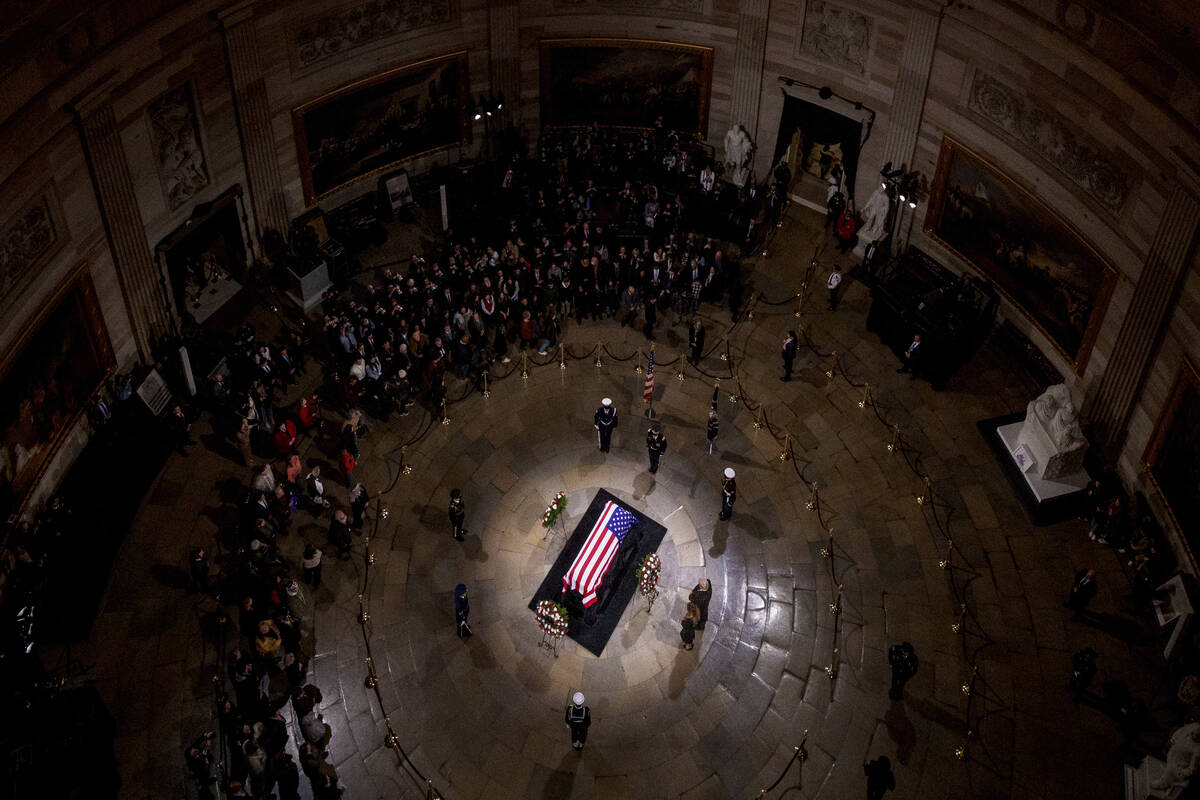 President-elect Donald Trump and Melania Trump pause at the flag-draped casket of former Presid ...