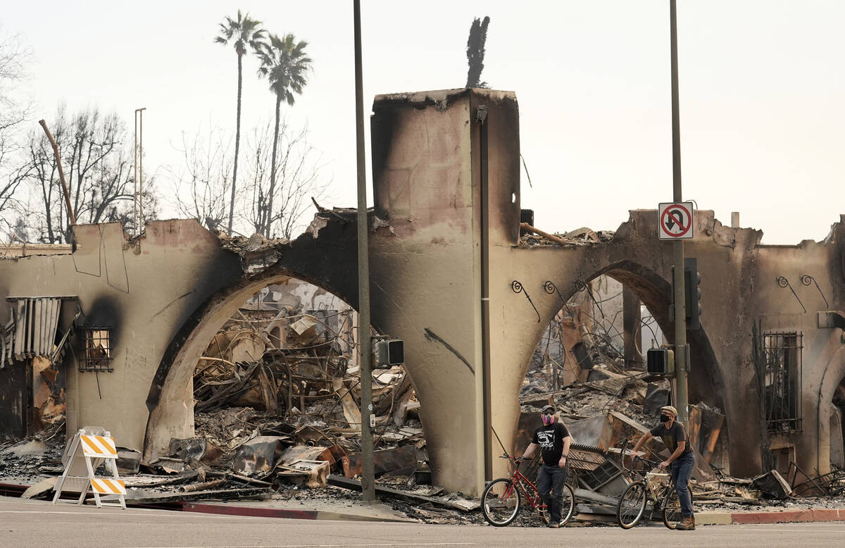 Cyclists move past a destroyed structure on Lake Avenue, Thursday, Jan. 9, 2025, in the downtow ...