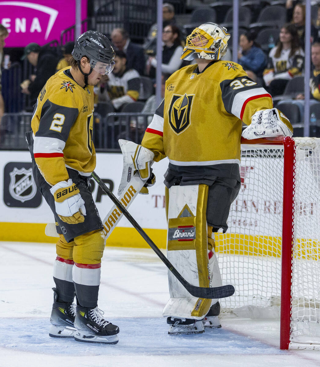 Golden Knights defenseman Zach Whitecloud (2) gives goaltender Adin Hill (33) a little boost wi ...