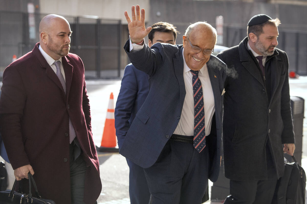 Rudy Giuliani, second from right, waves as he arrives at federal court in Washington, Friday, J ...