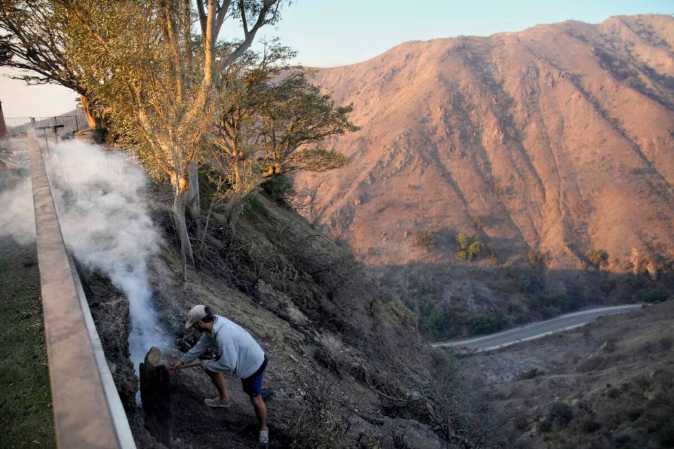 Garrett Yost gathers puts out hotspots from his neighbors' fire-ravaged properties in the after ...