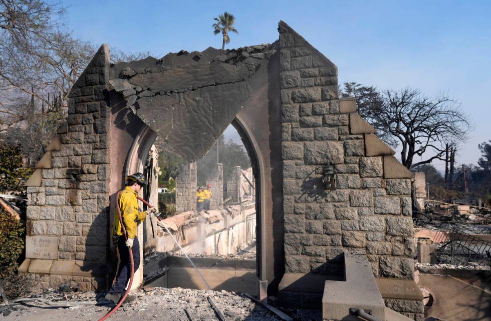 A firefighter hoses down the charred remains of St. Mark's Episcopal Church after it was destro ...