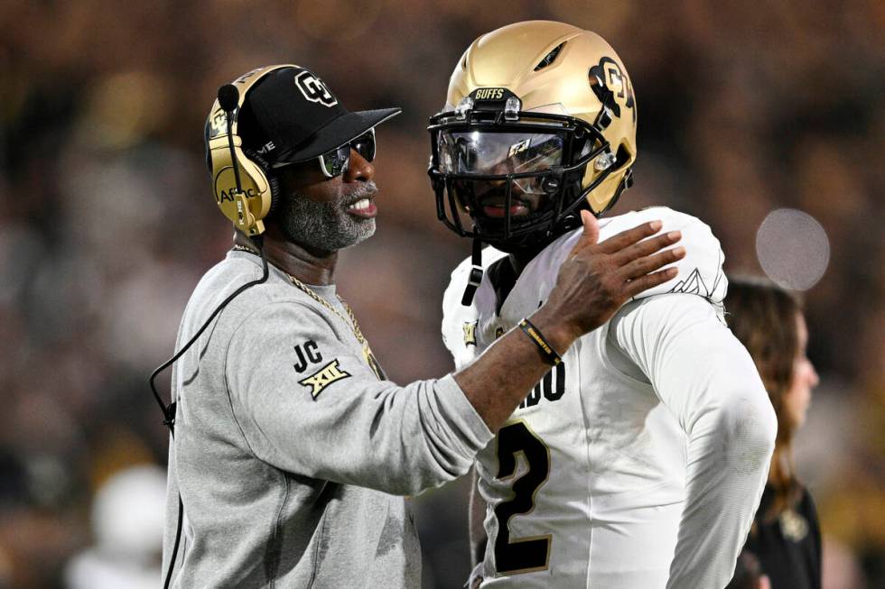 FILE - Colorado head coach Deion Sanders, left, talks with quarterback Shedeur Sanders (2) duri ...