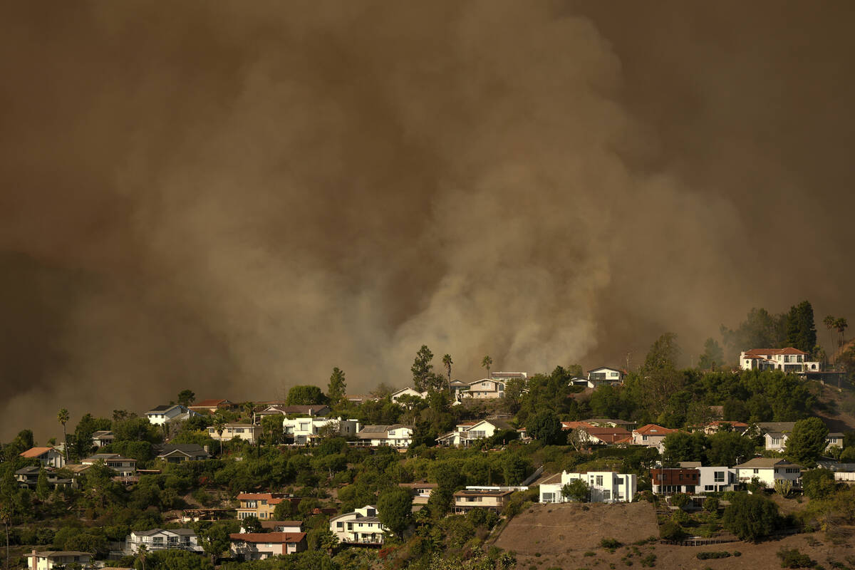 Smoke from the Palisades Fire rises over residences in Mandeville Canyon Saturday, Jan. 11, 202 ...