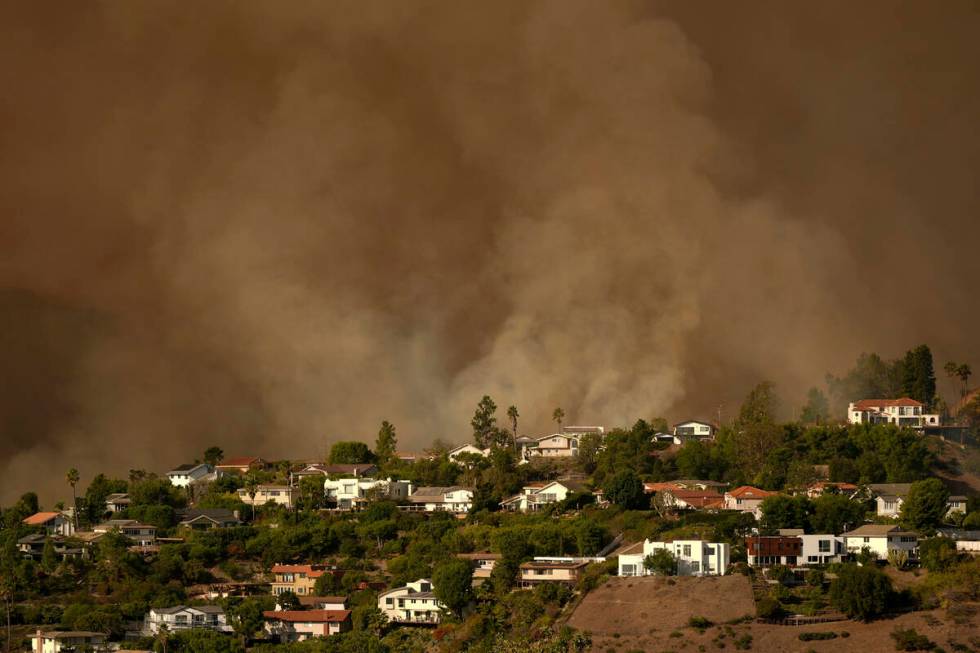 Smoke from the Palisades Fire rises over residences in Mandeville Canyon Saturday, Jan. 11, 202 ...