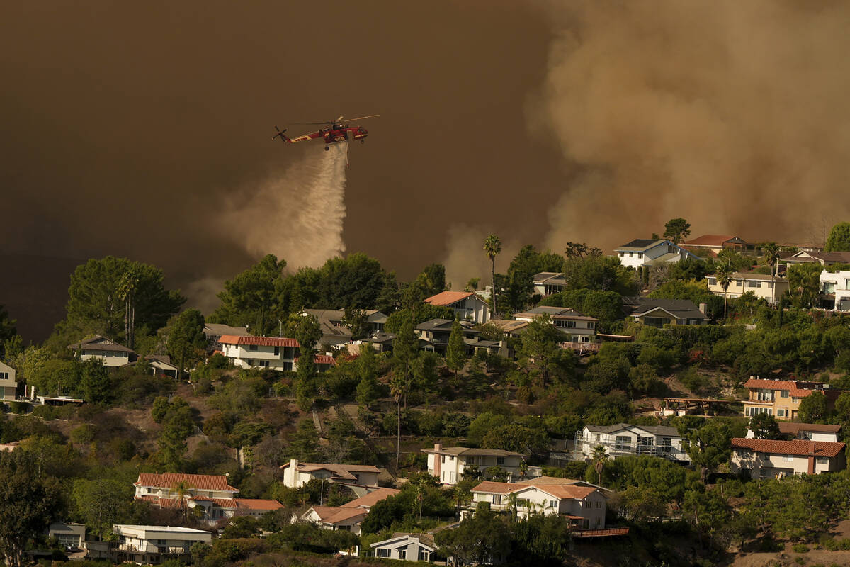 Water is dropped on homes as the Palisades Fire advances in Mandeville Canyon Saturday, Jan. 11 ...