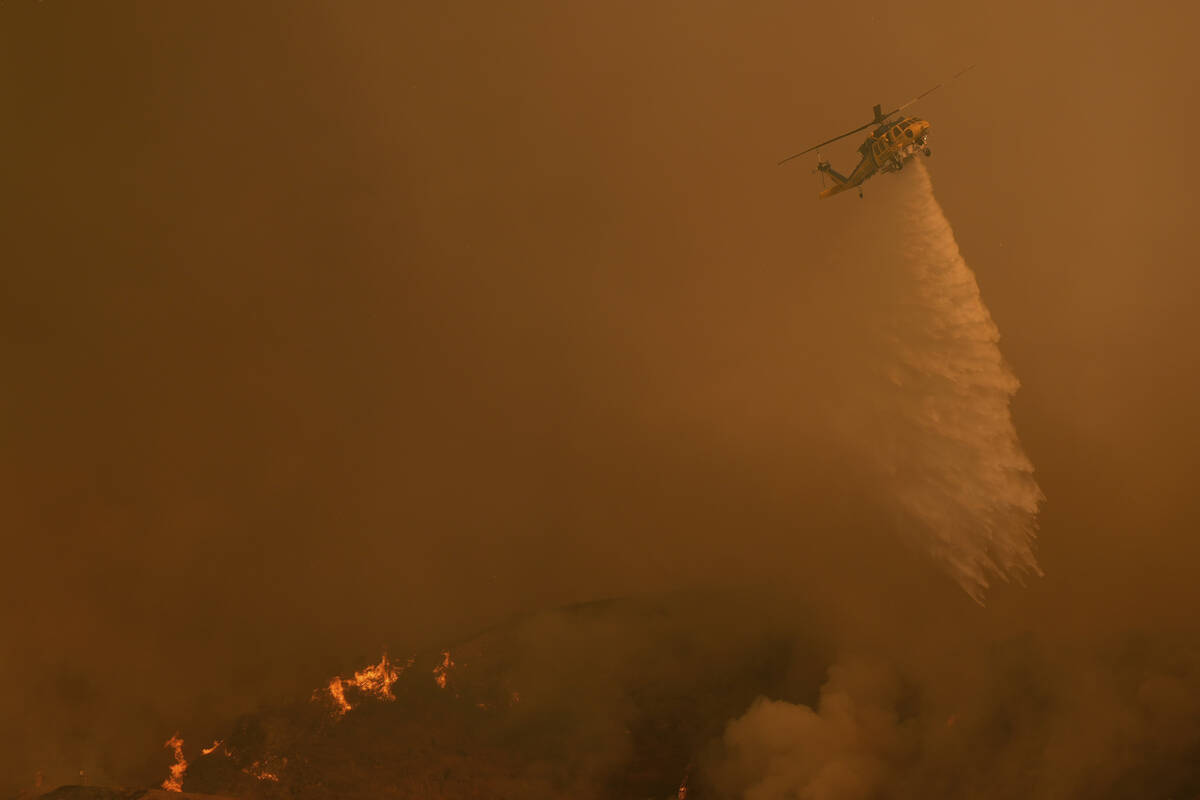 Water is dropped on the Palisades Fire by helicopter in Mandeville Canyon Saturday, Jan. 11, 20 ...