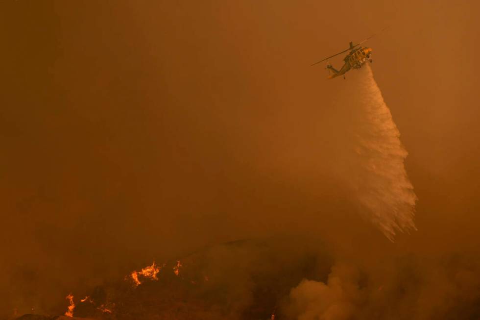 Water is dropped on the Palisades Fire by helicopter in Mandeville Canyon Saturday, Jan. 11, 20 ...