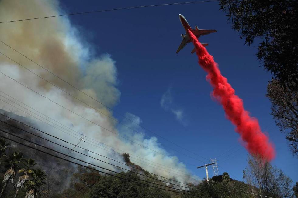 A Super Scooper drops phosphorus on the the Palisades fire as it tears through Mandeville Canyo ...