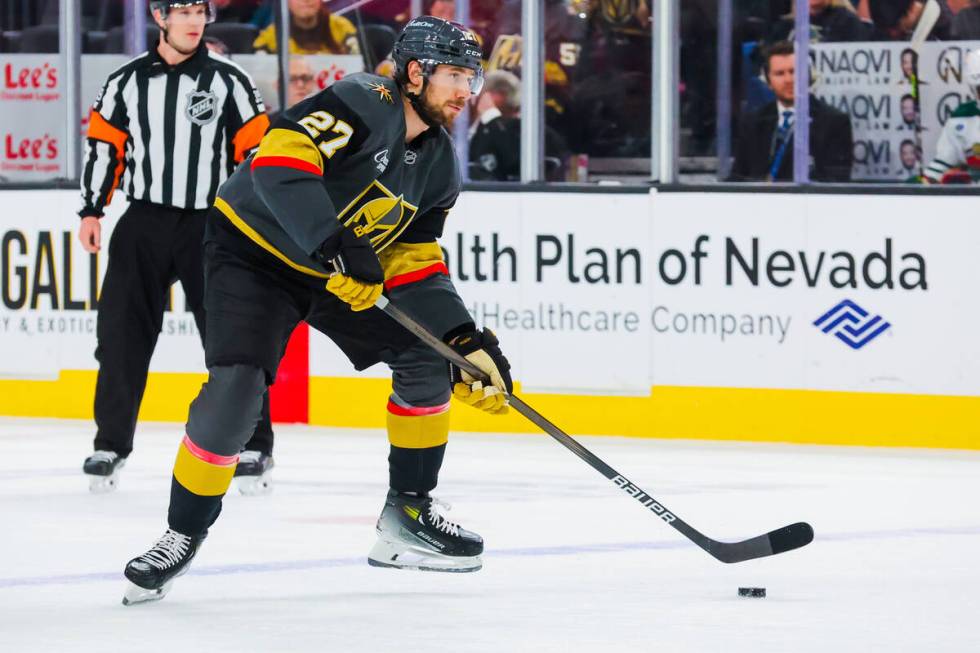 Golden Knights defenseman Shea Theodore (27) shuffles the puck during an NHL hockey game betwee ...