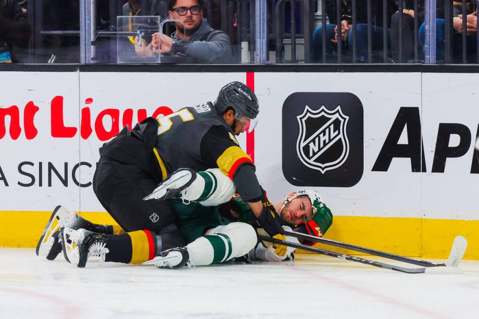 Golden Knights right wing Keegan Kolesar (left) falls onto Minnesota Wild defenseman David Jiri ...