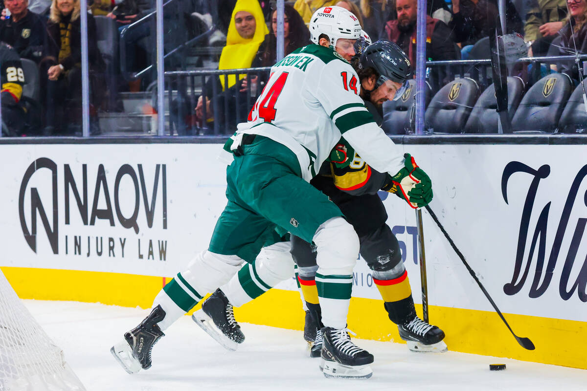 Golden Knights right wing Mark Stone (61) tries to force the puck away from Minnesota Wild defe ...