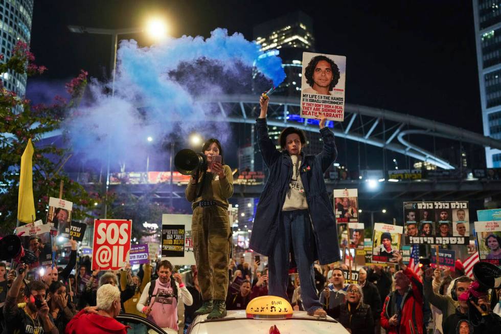 Demonstrators hold signs and flares during a protest calling for the immediate release of the h ...