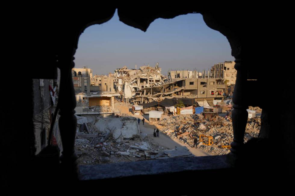 Palestinians walk through the destruction in the wake of an Israeli air and ground offensive in ...