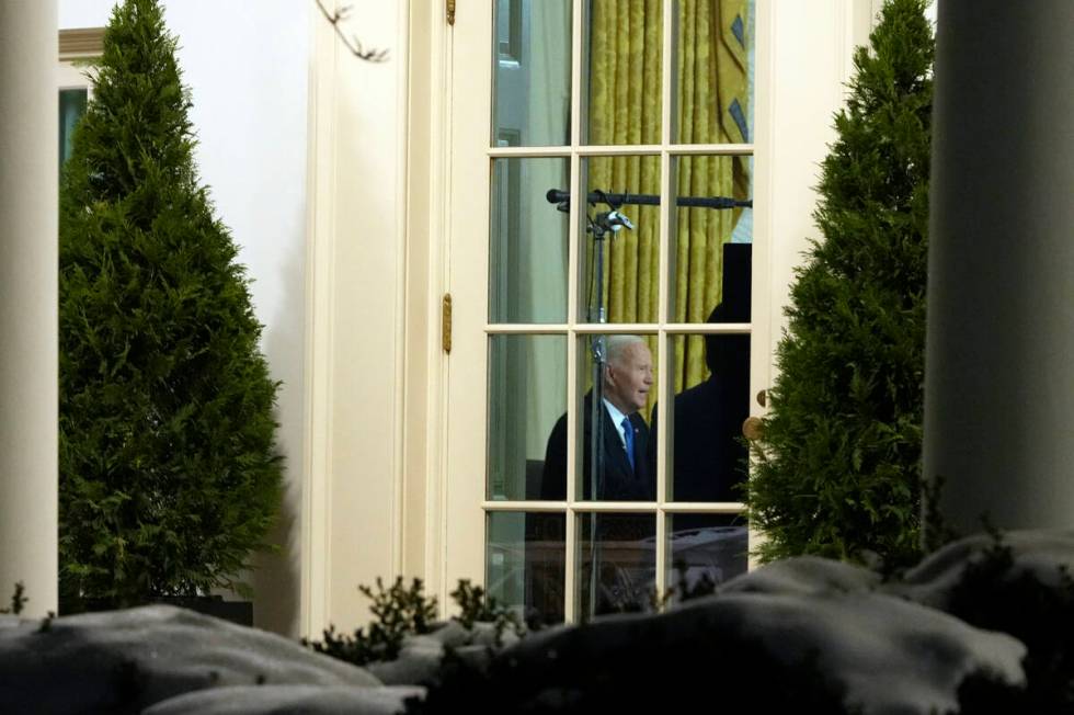 As seen through a window from the Colonnade outside the Oval Office, President Joe Biden speaks ...