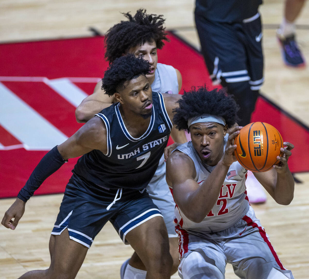 UNLV forward Jacob Bannarbie (12) runs down a loose ball over Utah State Aggies guard Dexter Ak ...