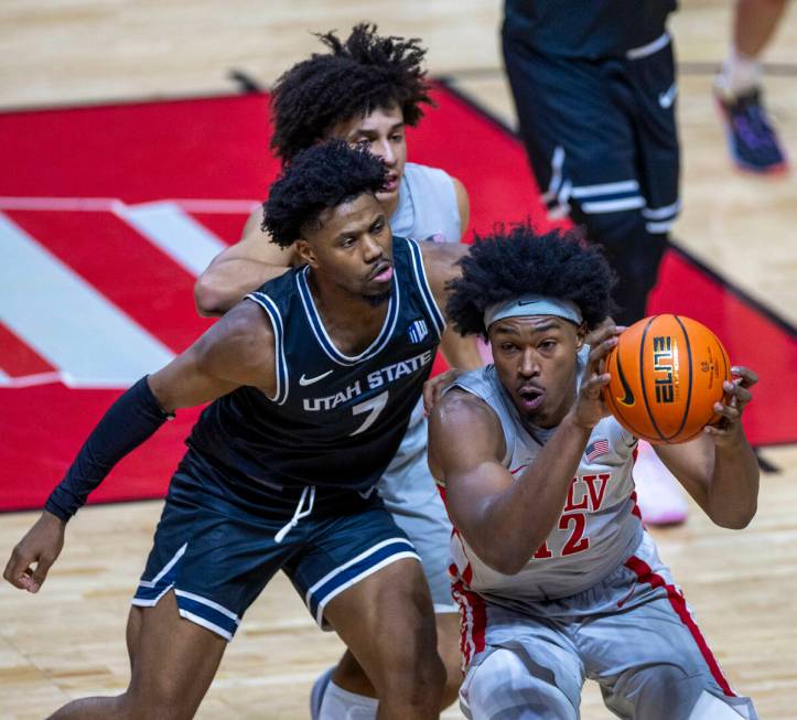 UNLV forward Jacob Bannarbie (12) runs down a loose ball over Utah State Aggies guard Dexter Ak ...