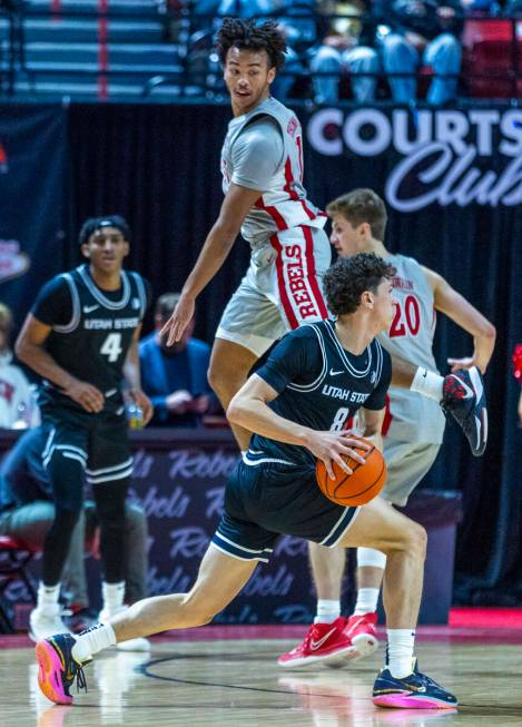 UNLV guard Dedan Thomas Jr. (11) leaps past Utah State Aggies guard Drake Allen (8) while defen ...