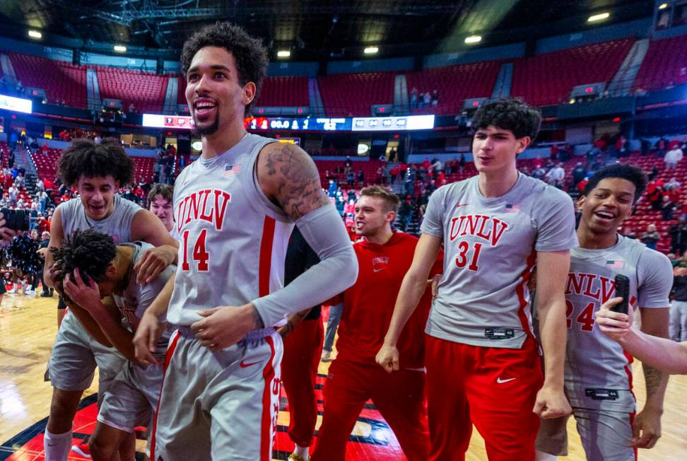 UNLV players celebrate their win against the Utah State Aggies following their NCAA men's baske ...