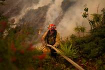 A firefighter sets up a hose while fighting the Palisades Fire in Mandeville Canyon on Saturday ...