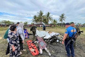 The body of a victim is covered with a blanket as members of security forces inspect the site w ...