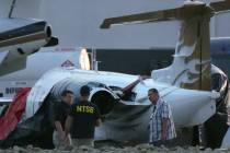 Investigators look at a crashed Learjet at Scottsdale Airport after it collided with a parked p ...