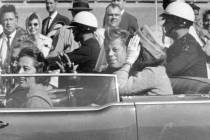 President John F. Kennedy waves from his car in a motorcade in Dallas, with first lady Jacqueli ...