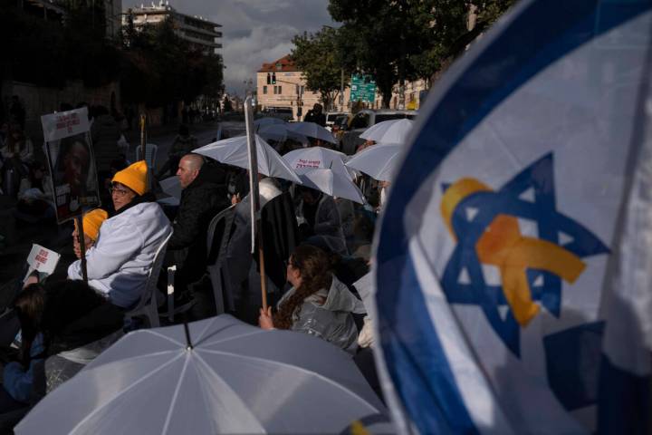 Activists sit on a road with white umbrellas during a protest calling for the release of hostag ...